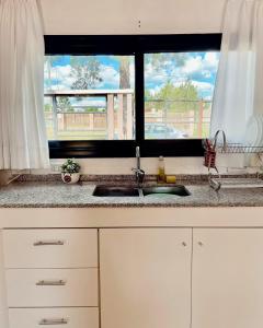 eine Küchentheke mit Spüle und zwei Fenstern in der Unterkunft Casa El Bosque in Candelaria