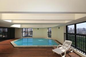 a house with a swimming pool and a chair at Flat Bienal Ibirapuera UH507 in Sao Paulo