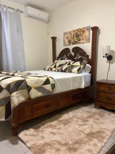a bedroom with a bed with a comforter and a table at Tranquil Oasis in Mona in Kingston