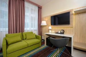 a living room with a green couch and a television at Stay inn Hotel Gdańsk in Gdańsk