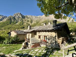 an old stone house with mountains in the background at La Mizoùn de Marguerito - Appartamento Rododendro in Acceglio