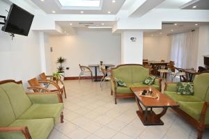 a waiting room with chairs and tables and a tv at Hotel Globo in Durrës