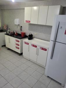 a kitchen with white cabinets and a white refrigerator at Hostel Kaizen in Curitiba