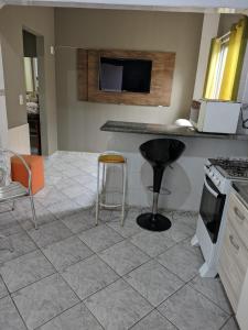 a kitchen with a counter and stools in a room at Casa de família e Quarto in Balneário Camboriú