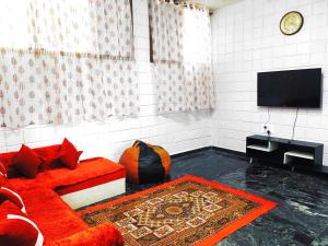a living room with a red couch and a flat screen tv at Mannat Inn TS Mysore - Premium Homestay in Mysore