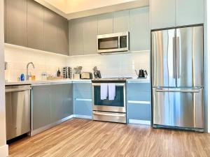 a kitchen with blue cabinets and a stainless steel refrigerator at Designer Hollywood Penthouse with Private Balcony on Sunset in Los Angeles