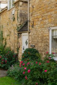 a stone house with pink flowers in front of it at The Farthings Cotswolds Holiday Cottage in Chipping Campden