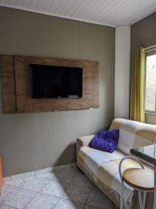 a living room with a couch and a flat screen tv at Casa de família e Quarto in Balneário Camboriú
