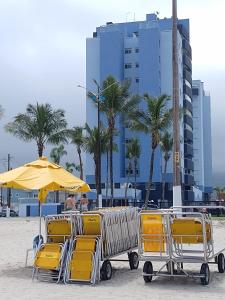 eine Gruppe von Stühlen und einem Sonnenschirm am Strand in der Unterkunft Espaço Sol, Mar & Cia in Bertioga