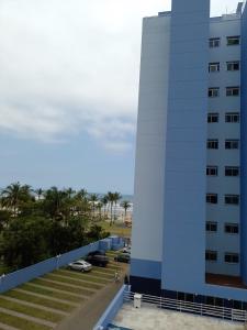 ein hohes weißes Gebäude neben einem Parkplatz in der Unterkunft Espaço Sol, Mar & Cia in Bertioga