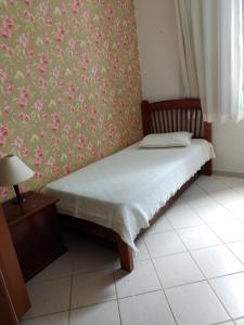 ein Schlafzimmer mit einem Bett mit Blumen an der Wand in der Unterkunft Espaço Sol, Mar & Cia in Bertioga