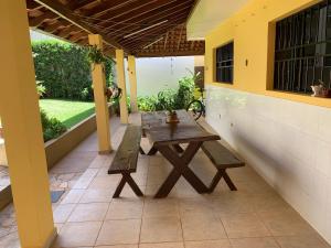 a wooden picnic table on the patio of a house at Excelente propriedade com belo jardim! in Presidente Prudente