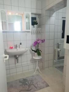 a bathroom with a sink and a vase of flowers on a table at FeWo Goslar Harz in Goslar