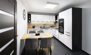 a kitchen with white cabinets and a wooden table and chairs at Luxus apartmán pod hradom in Kežmarok