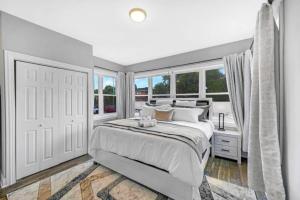 ein weißes Schlafzimmer mit einem großen Bett und Fenstern in der Unterkunft Spacious Haven 8-Min to Chicago Sleeps 10 in Forest Park
