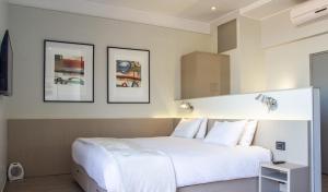 a bedroom with a large white bed with three pictures on the wall at Novapark in Santiago