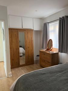 a bedroom with a bed and a dresser and a mirror at Sixty Four in The Mumbles
