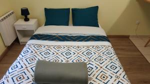 a bed with blue pillows in a room at Bonvallet - Studio paisible et chaleureux avec balcon in Amiens