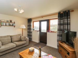 a living room with a couch and a tv at Brindle Cottage in Lydiard Millicent