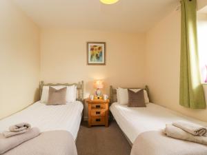 two twin beds in a room with a table at Brindle Cottage in Lydiard Millicent