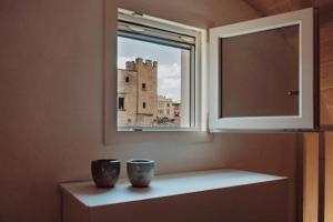 two vases sitting on a shelf under a window at Il Maniero casa vacanze by MOH in Grottaglie