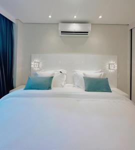 um quarto com uma grande cama branca com almofadas azuis em Moema Times Square SP - Luxury Suíte em São Paulo