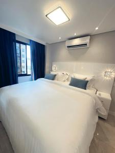 um quarto com uma grande cama branca e uma janela em Moema Times Square SP - Luxury Suíte em São Paulo