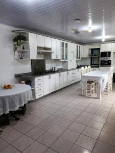 una cucina con armadi bianchi, tavolo e sedie di Casa com piscina em Torres/RS a Torres