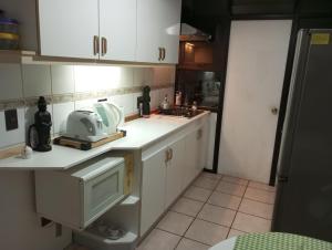 eine kleine Küche mit weißen Schränken und einer Mikrowelle in der Unterkunft Hostal Rucatremo in Curicó