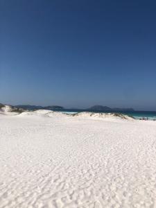 a white sandy beach with the ocean in the background at Férias em Família Apartamento Temporada in Cabo Frio