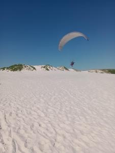 a person flying a kite over a sandy beach at Férias em Família Apartamento Temporada in Cabo Frio