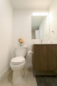 a bathroom with a toilet and a sink and a mirror at Vibrant & Modern Loft-style Walkout Near LRT in Calgary