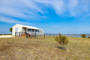 uma pequena casa branca numa colina perto da água em High View Family Cottages em Warrnambool