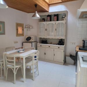 uma cozinha com armários brancos e uma mesa e cadeiras em El Abuelo Angel em Ribadavia