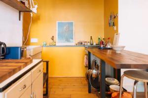 a kitchen with a counter and a yellow wall at Peaceful 1BD Flat with Private Garden Brighton! in Brighton & Hove