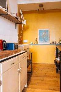 a kitchen with a yellow wall and a counter at Peaceful 1BD Flat with Private Garden Brighton! in Brighton & Hove