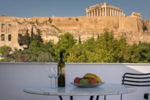 a table with a bottle of wine and a bowl of fruit at Acropolis and Odeon Panorama in Athens