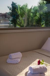 a bed with towels and a flower and a window at Acropolis and Odeon Panorama in Athens