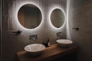 two sinks in a bathroom with two mirrors at Maria Rosa Suites in Victoria