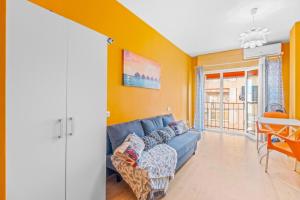 salon z niebieską kanapą i żółtymi ścianami w obiekcie Studio a 199m de la playa los Locos w mieście Torrevieja