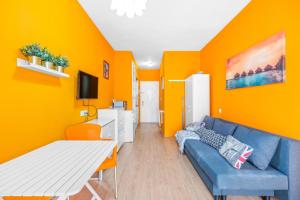 salon z niebieską kanapą i pomarańczową ścianą w obiekcie Studio a 199m de la playa los Locos w mieście Torrevieja