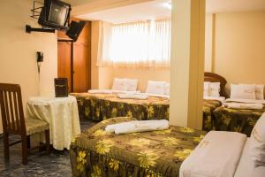 ein Hotelzimmer mit 3 Betten und einem TV in der Unterkunft Hotel Presidencial in Chiclayo