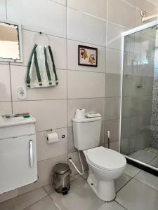 a white bathroom with a toilet and a shower at Quitieenete Arraial do Cabo in Arraial do Cabo