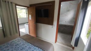 sypialnia z łóżkiem i telewizorem na ścianie w obiekcie Pousada Moinho D'água w mieście Guarapari