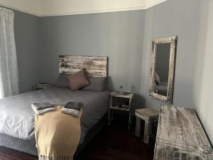 - une chambre avec un lit avec un miroir et une table dans l'établissement Plantation House, Boksburg, à Boksburg