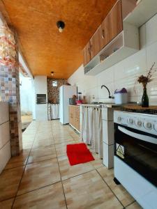 a kitchen with white appliances and a red rug on the floor at Na Casa Delas Jeri - com Churrasqueira in Jericoacoara
