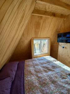 sypialnia z łóżkiem i oknem na poddaszu w obiekcie Cabañas Verde Pirámide w mieście Ñilque