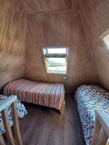 um pequeno quarto com uma cama e uma janela em Cabañas Verde Pirámide em Ñilque