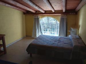 een slaapkamer met een bed en een groot raam bij Cabañas la Casa del Tata in Potrero de los Funes