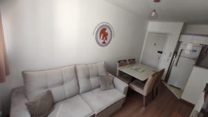 a living room with a white couch and a table at Apartamento Novinho Aeroporto JF in Juiz de Fora